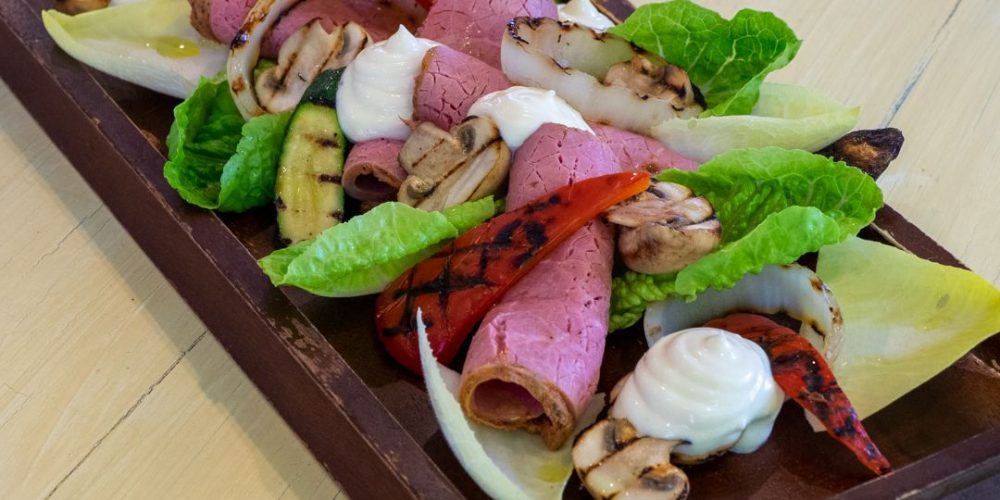 Salad with pastrami on wooden board
